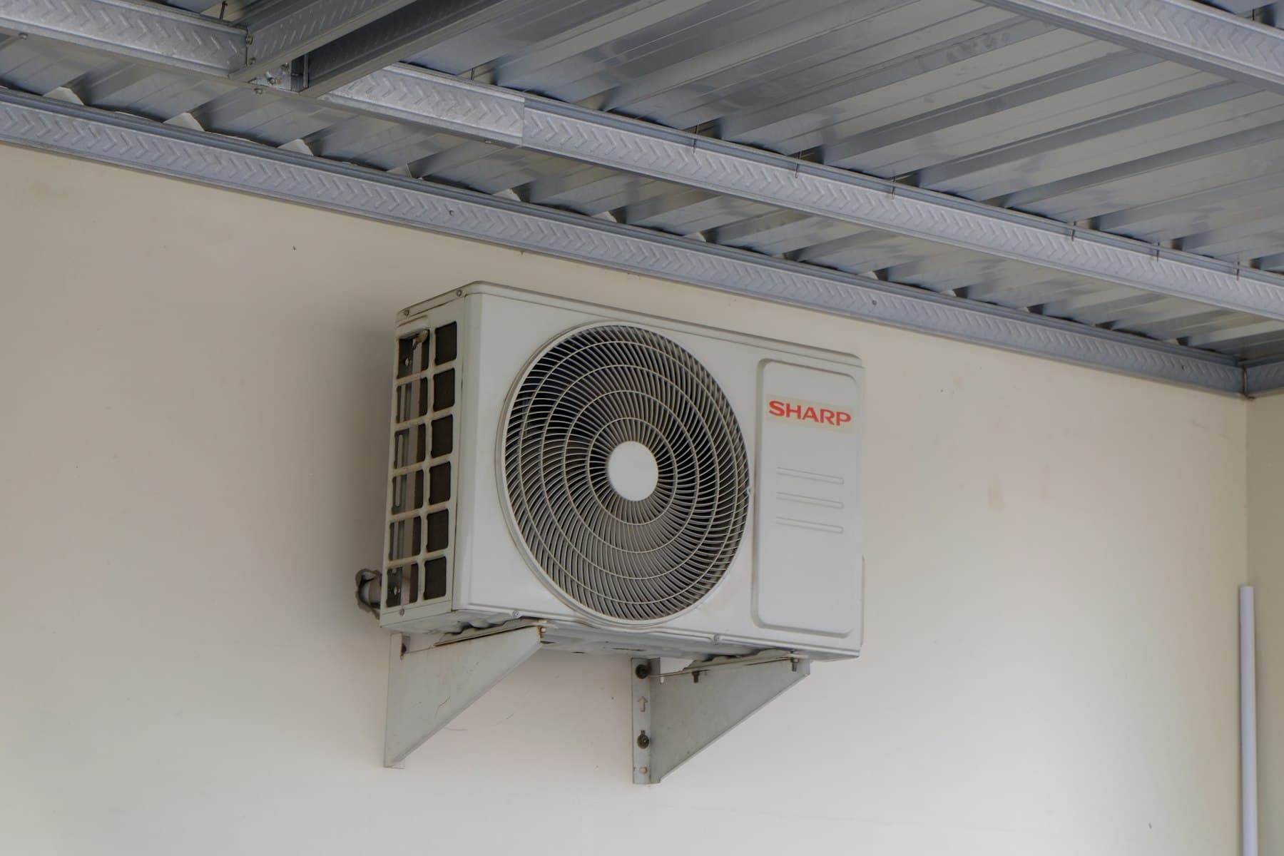 Unidad exterior de aire acondicionado asegurada con soportes en una pared